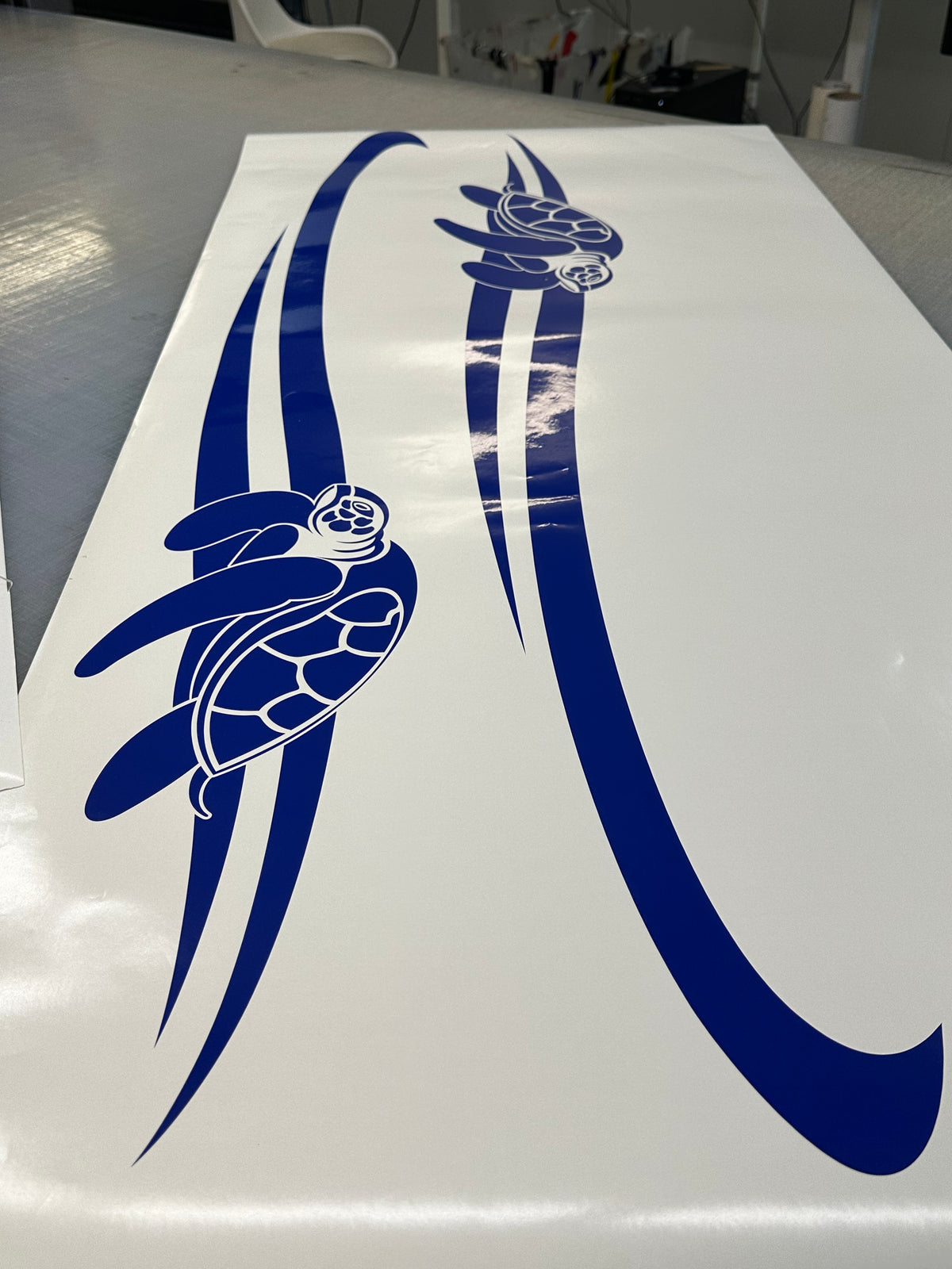 A set of two blue vinyl stickers with a turtle design and stripes, intended for use on vehicles such as boats and caravans.