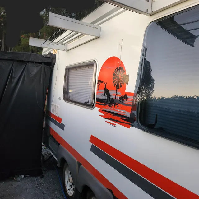 Van with a sunset design on the side, parked outdoors.