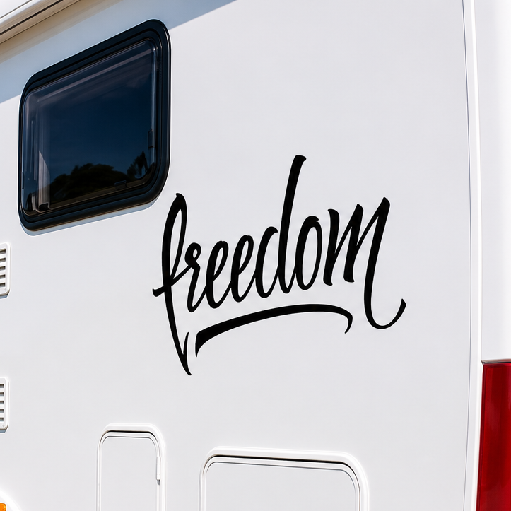 Freedom vinyl decal sticker applied to the side of a white motorhome parked by the coast