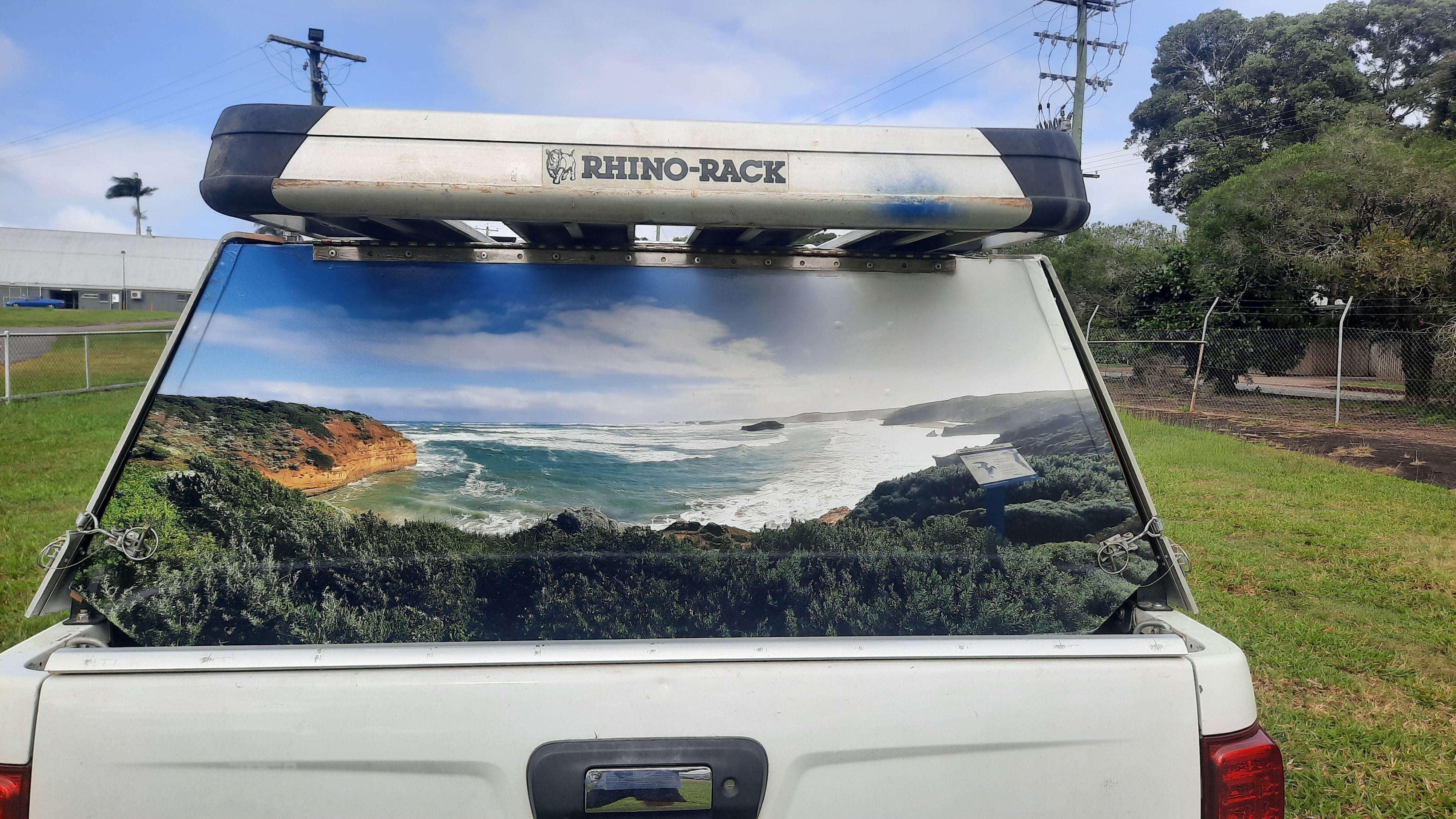 Mega Sticker Store custom vinyl decal featuring a coastal landscape photo applied to a white 4WD canopy rear window.