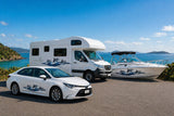 Mega Sticker Store dolphin stripe vinyl decals applied to a white car, motorhome, and boat by the coast.