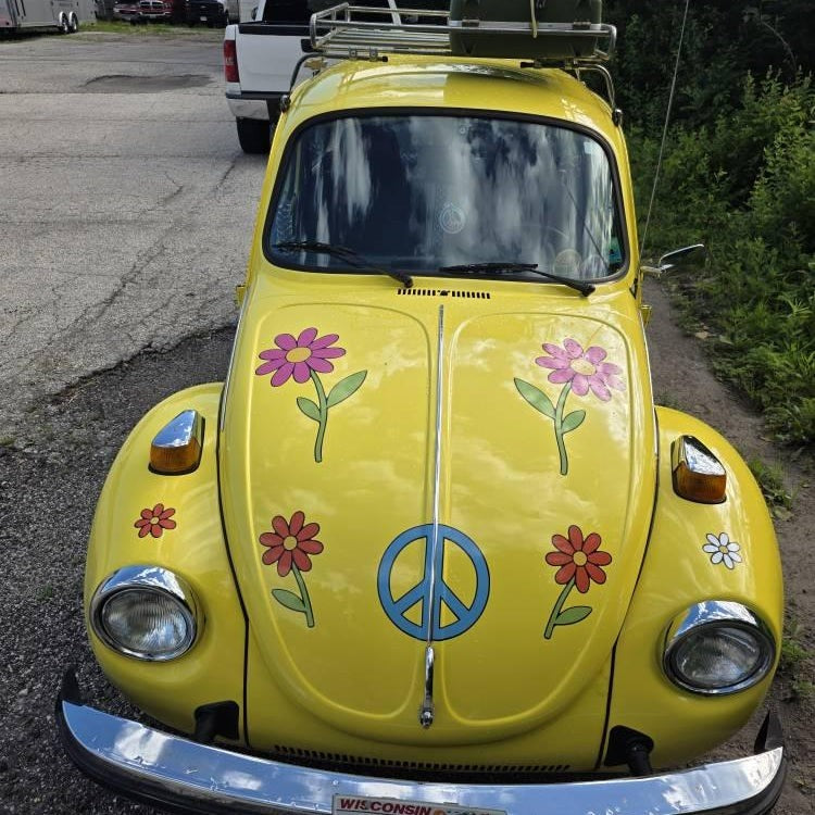 Mega Sticker Store yellow vintage car decorated with retro hippie flower and peace sign vinyl decals.