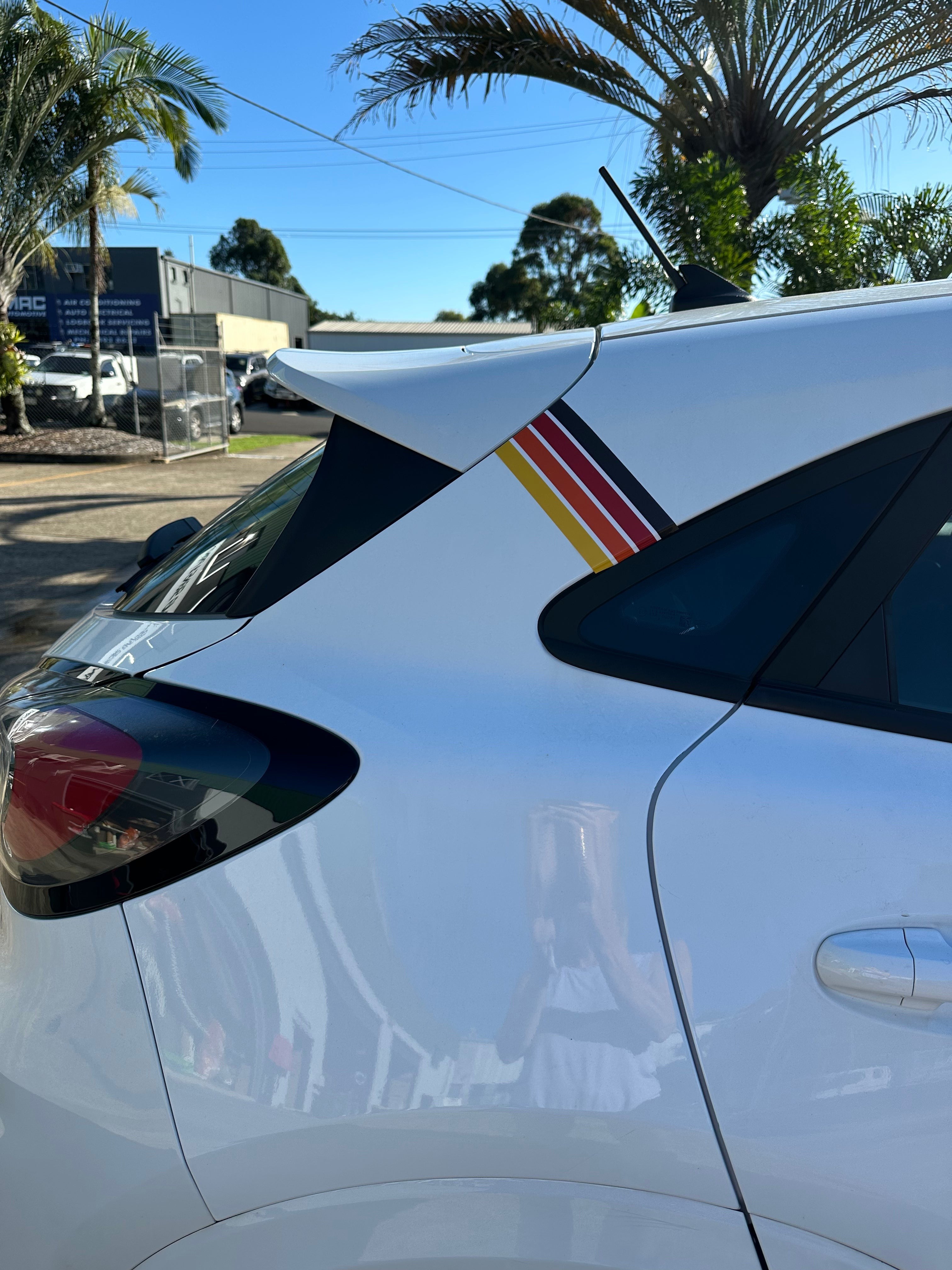 Mega Sticker Store retro pinstripe decal with orange, yellow, and black stripes applied to a white car rear pillar